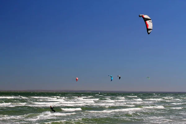 Kitesurf en las olas del mar. Vista panorámica de la gente practicando kitesurf — Foto de Stock