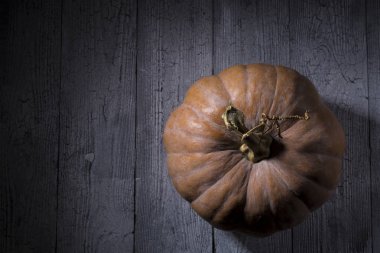 Yukarıdan ahşap arka plan görünümünde büyük bir turuncu kabak. Şükran günü ve Cadılar Bayramı balkabağı