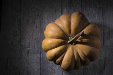 Yukarıdan ahşap arka plan görünümünde büyük bir turuncu kabak. Şükran günü ve Cadılar Bayramı balkabağı