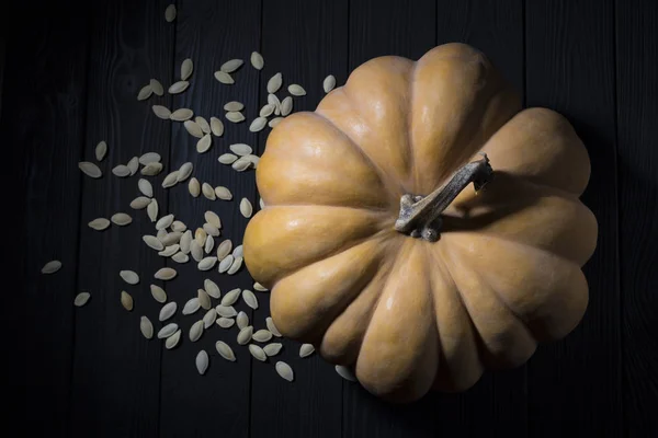 Une grande citrouille avec des graines sur une table en bois. Vue ci-dessus — Photo