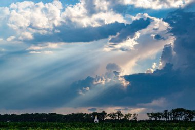 Tarladaki Hıristiyan kilisesi güneş ışınlarıyla aydınlatılıyor yağmur bulutlarını delip geçiyor..