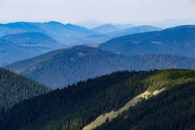 Güneşin ışınlarıyla aydınlanan puslu dağlar bulutlu gökyüzünden kırılıyor..