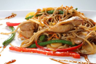 Beyaz tabakta kızarmış tavuk ve sebzeli soya eriştesi..