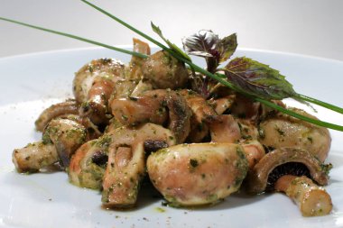 Pesto soslu pişmiş şampiyonlar ve beyaz tabakta fesleğen..