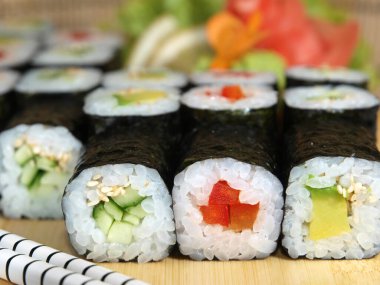 Japon maki rulo seti avokado, salatalık ve kırmızı dolma biber ile ahşap tepside yakın çekim.