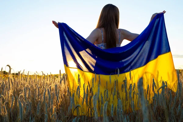 小麦の間のフィールドにウクライナのフラグを持つ女の子 — ストック写真