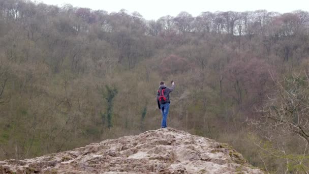 Jeune homme debout sur un rocher essayant d'attraper un signal sur le téléphone portable — Video