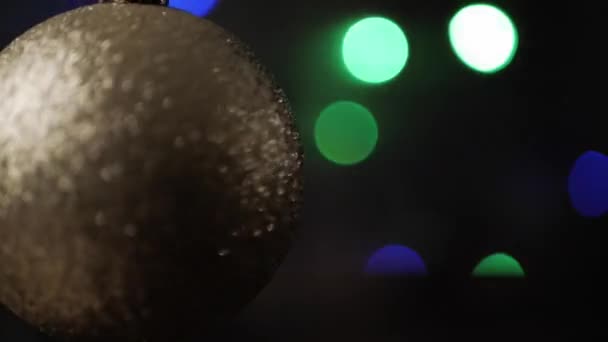 Rack se concentrer sur la boule de Noël en argent au premier plan. Clignotant lumières de Noël bokeh en arrière-plan. Gros plan . — Video