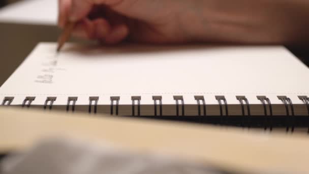 Vrouw maakt aantekeningen met potlood in dagboek. Close-up. Beweging van de schuifregelaar. — Stockvideo