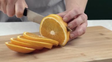 Dişi eller kesme tahtasında portakal keser. Yakın çekim