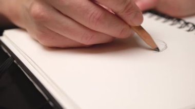 Kadın el çizim iyla kalemile çizim defterinde. Yakından kapatın. Kaydırıcı hareketi