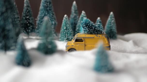 Winter Forest miniatuur met een kleine gele speelgoed auto met een kerstboom op het dak, dubbeldekker rode bus, sneeuwlaag en kerstbomen. — Stockvideo