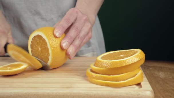 Kvinnliga händer skära en orange på skärbräda. Närbild skjutreglage rörelse — Stockvideo