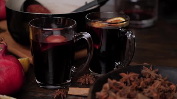Female hands put slices of oranges and anise stars in clear glass mugs with mulled wine. Close up slider movement. — Stock Video