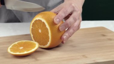 Kadın eli kesme tahtasıyla sulu portakalı kesiyor. Kapat.