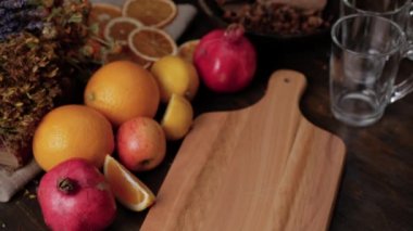 Kadın bir tencere sıcak sıcak şarabı kesme tahtasına koyuyor. Taze limon, portakal, nar ve kurumuş otlar. Şarabın buharı tencerenin üzerinde süzülüyor.