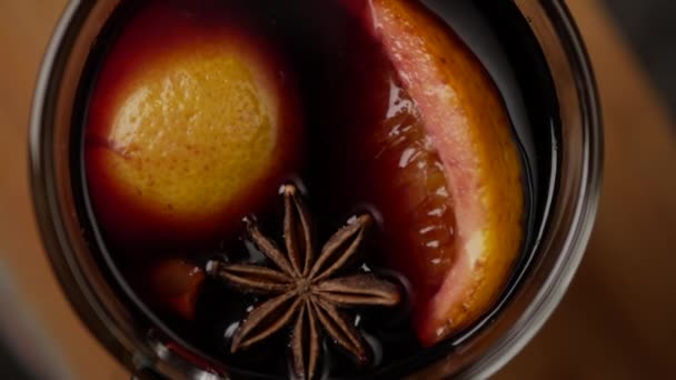 Fırıl fırıl dönen cam bardakla sıcak şarabın üst görüntüsü. Asma yüzeyi üzerinde anasonlu yıldız ve bir dilim portakal. Kapat. — Stok video