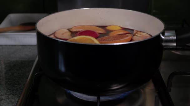 Bereiding van glühwein. Steelpan met rode wijn staat op het gasfornuis en begint te koken. Stoom uit wijn zweef over de pan — Stockvideo