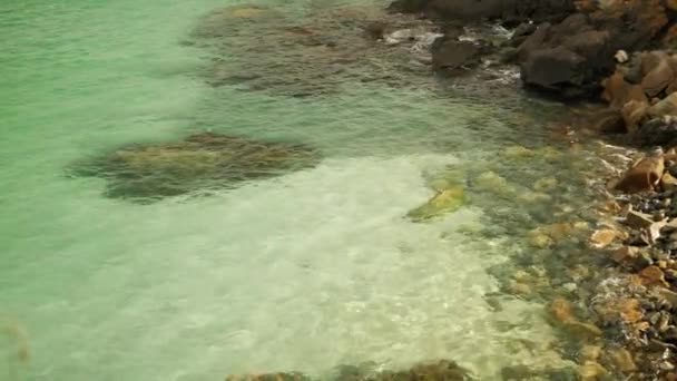 Havsvågor som kraschar på stenig strand. Sand och stenar kan ses genom vattnet — Stockvideo