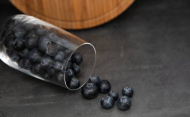 Cam bir kapta taze yaban mersini. Lezzetli yaban mersini bir cam bardak dağınık. Arka planda gri arka plan ahşap bir tahta. Tex için yer