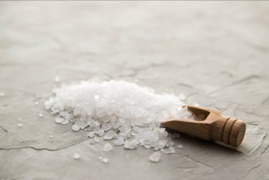 Ahşap kepçe deniz tuzu kristalleri beton arka plan üzerinde yakın çekim. Deniz tuzu ile küçük kürek. Metin için yer
