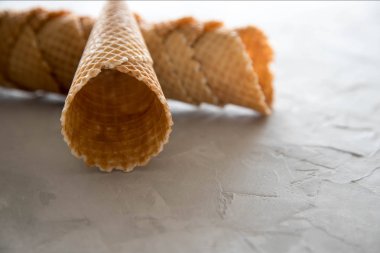 Boş bir waffle bardağı diğer waffle bardak yatıyor. Beton gri arka plan üzerinde dondurma için boş waffle fincan bir parça yakın çekim