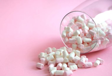 bir cam bardak beyaz ve pembe marshmallows. bir cam kadeh içinde marshmallows