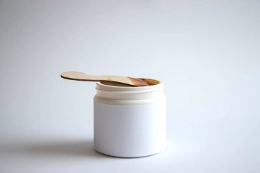 Depilasyon ve güzellik konsepti - şeker macunu veya ahşap balmumu spatula ile beyaz plastik bir kavanozda epilasyon için balmumu