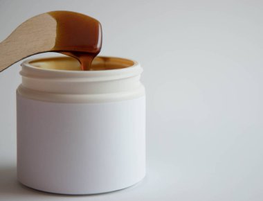 Depilasyon ve güzellik kavramı - erimiş hamur ahşap balmumu spatula ile beyaz plastik bir kavanozda epilasyon için şeker macunu veya balmumu. Kopyalama alanı