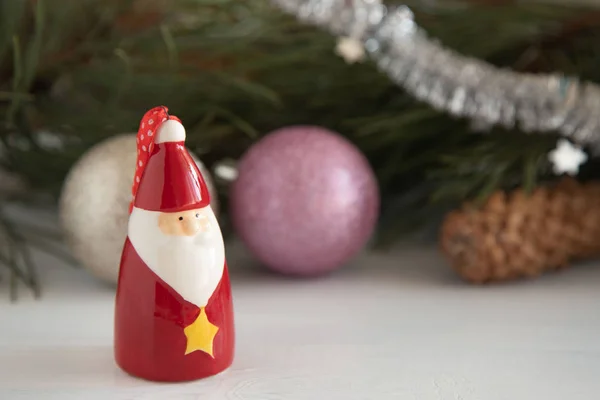Keramická figurína vánoční výzdoby Santa Clause na rozmazané pozadí vánočních hraček na bílém dřevěném stole. Vánoční stromek Santa Claus. — Stock fotografie