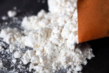 koyu bir arka plan üzerinde bir çanta dan dökülen yakın çekim un. Beyaz un