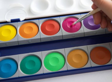 çok renkli parlak boyalar ve bir çocuğun elinde bir fırça. Çocuklarla çizim kavramı, erken çocukluk gelişimi.