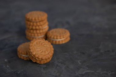koyu bir arka plan üzerinde krem bir tabaka ile yuvarlak shortbread çerezleri. Arka planda, bulanık bir tanımlama bilgisi yığını. Kopyalama alanı