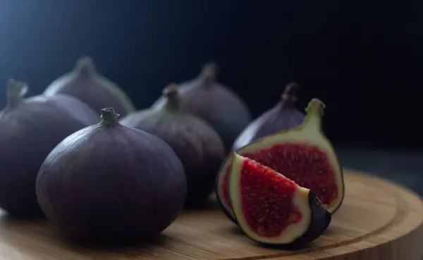 Słodkie i świeże owoce figowe leżą na drewnianej płycie na ciemnym tle. Zdjęcie o niskim kluczu. Miejsce na tekst — Zdjęcie stockowe