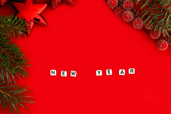 Zielone gałązki sosny z czerwonymi zabawkami świątecznymi i napis Nowy Rok na kostkach na czerwonym tle. Koncepcja Nowego Roku. Miejsce na tekst — Zdjęcie stockowe