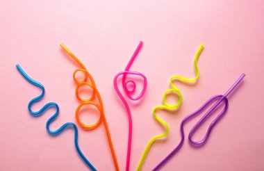 Pembe arka planda değişik şekilli çok renkli borular. Mavi, turuncu, sarı, ahududu ve mor pipetli. Tatil Konsepti