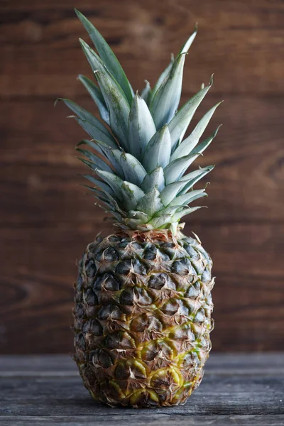 Pineapple close-up on a wooden background. Tropical fruit. Vertical orientation