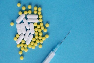 Haplar, haplar, kapsüller, antibiyotikler, ilaçlar ve şırınga. Tıbbi konsept. Mavi arka plan. Metin için yer.