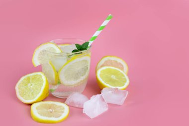 Ferahlatıcı bir içecek, limonata ya da limonlu su bardakta ve yakınlarda buz ve limon parçaları. Yaz kokteylleri. Boşluğu kopyala