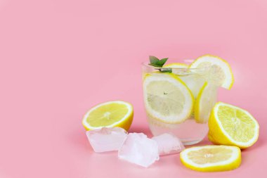 Limon, buz ve bir sıra dilimle ferahlatıcı su pembe zemin üzerinde turunçgil ve buz dilimleri. Boşluğu kopyala.