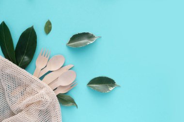 Çevre dostu tek kullanımlık kaşıklar, çatallar, bıçaklar, pamuk iplik torbası ve yeşil yapraklı bulaşık fırçası. Sıfır kayıp. Çevre kirliliği. Metin için yer.