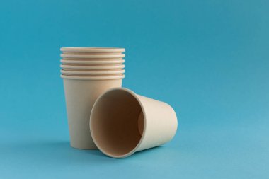 Mavi arka planda çevre dostu tek kullanımlık kağıt bardaklar. Ekoloji, sıfır atık kavramı. Metin için yer.