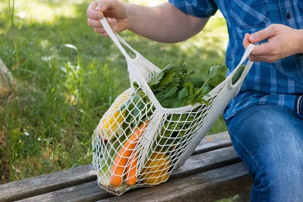 Un homme ouvre un sac en coton sur un banc dans un parc. Gros plan. Aucun gaspillage. Matériau biodégradable. Prendre soin de l'écologie et de l'environnement, respect de la nature. — Photo