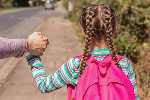 Back to school. Close-up A dad, father or parent is seeing off or leading his daughter with a backpack or knapsack to school down the street and holding her hand. first day of school, new school year. — Stock Photo, Image