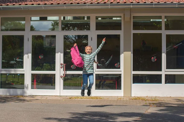 The schoolgirl is jumping for the joy of returning to school. The beginning of the school year. Education after vacation and coronavirus epidemic.