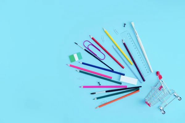 Papeterie, crayons de couleur saupoudrés d'un panier sur fond bleu, vue de dessus. Espace de copie. Achats à l'école avec papeterie — Photo