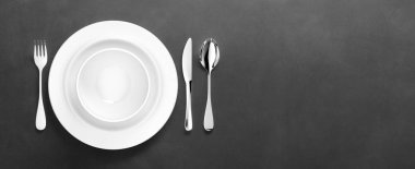 Gümüş çatal bıçaklı beyaz porselen yemek takımı.