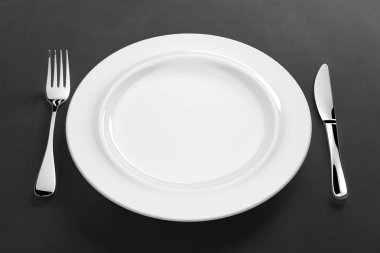 Gümüş çatal bıçaklı beyaz porselen yemek takımı.