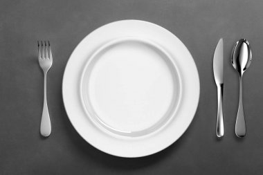 Gümüş çatal bıçaklı beyaz porselen yemek takımı.