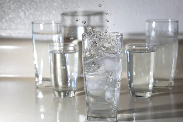 Ghiaccio Spruzzato Bicchiere Acqua Circondato Altri Bicchieri — Foto Stock